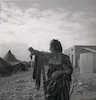 אשה לבושה בלבוש תוניסאי מסורתי פותחת את ברז המים המשותף בישוב – הספרייה הלאומית