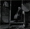 קשישה יושבת בפתח ביתה בגדרה – הספרייה הלאומית