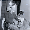 קשישה יושבת בפתח ביתה בגדרה – הספרייה הלאומית