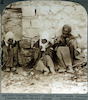 גבר ושני נערים מצורעים יושבים על הרצפה, מחוץ לירושלים.