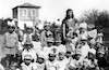 ילדי הגן בכנרת עם הגננת נעמי אחות חנה יזרעאלי ברקע בניין ביה"ס חג פורים 1928