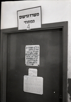 דלת משרד הרישום המחוזי עם שלטים בעברית ובידייש בין השאר פנייה לחוזרים מן השבי