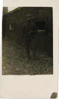 Soldier smoking a cigar stand in front of the barracks.