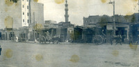 מבני אבן ומינרט (במרכז) ועגלות רתומות לסוסים ברחוב מרכזי, מצרים.