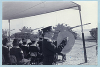 נגן תזמורת משטרת ישראל עם מצילתיים, על רקע שיירת טנקים במצעד צבאי.
