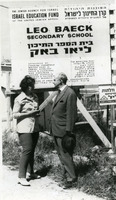 ד"ר מאיר (מקס) אלק עם הילדה שינדלר מתחת לשלט להקמת מבנה חדש לבית הספר "ליאו באק", חיפה.