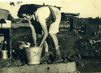 אישה רוחצת בדלי בחוץ.