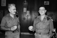 אלוף שלמה גזית, ראש אמ"ן היוצא, מרים כוסית לחיי יורשו, אלוף יהושע שגיא, בטקס חילופי התפקידים בקנטינה של בסיס צבאי.
