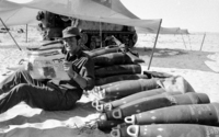 Reading a newspaper sittng next to the cannon shells.