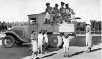 חיילים בריטים עם מקלע לואיס על משאית של קיבוץ עין החורש ונהג חבר הקיבוץ. לידם קבוצת ילדים ומטפלת